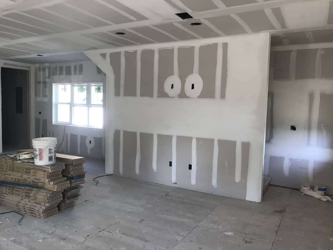 Drywall finishing and taping work in progress showing mud application on walls and ceiling