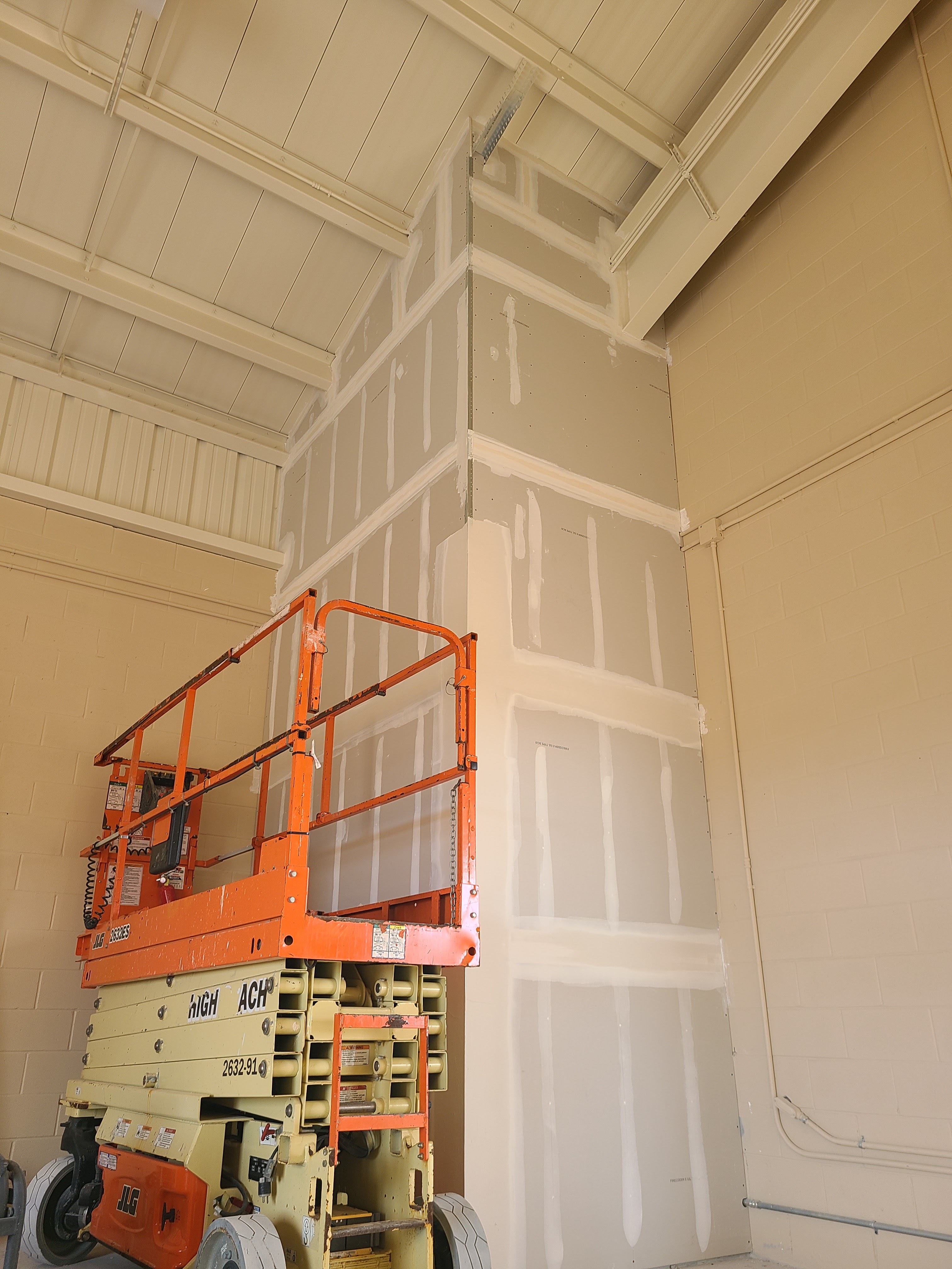 Commercial drywall project with scissor lift for high ceiling finishing